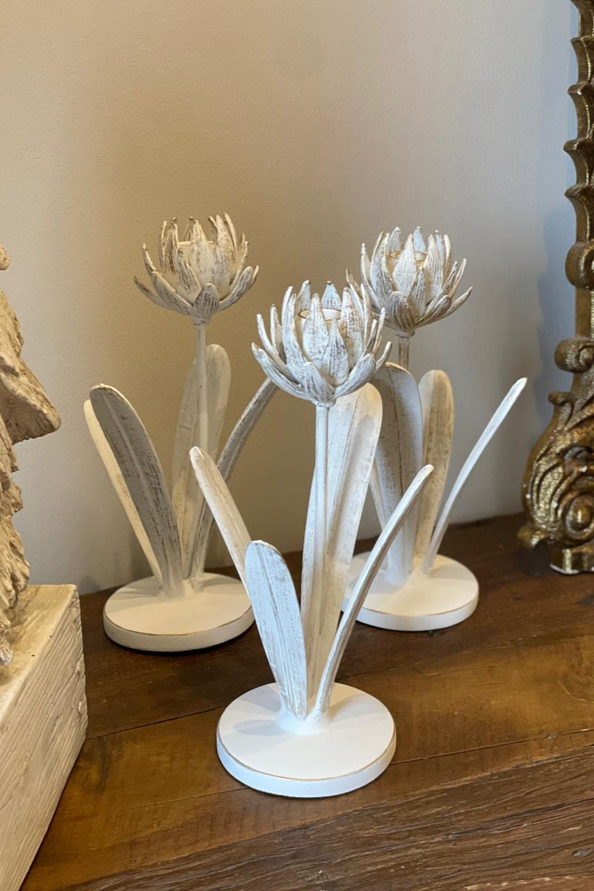Candelabro decorativo de metal con diseño de flor en acabado blanco envejecido para vela de candelero, ideal para decorar mesas, bibliotecas y consolas.