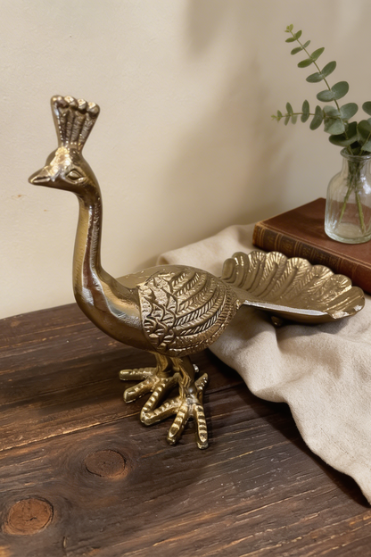 Figura decorativa de pavo real en metal dorado para decorar salas, bibliotecas, consolas o recibidores.
