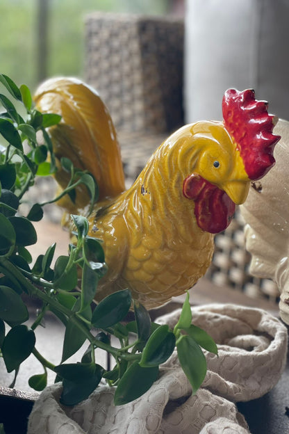 Gallo decorativo amarillo en cerámica esmaltada con detalles rojos y base metálica para decoración del hogar.
